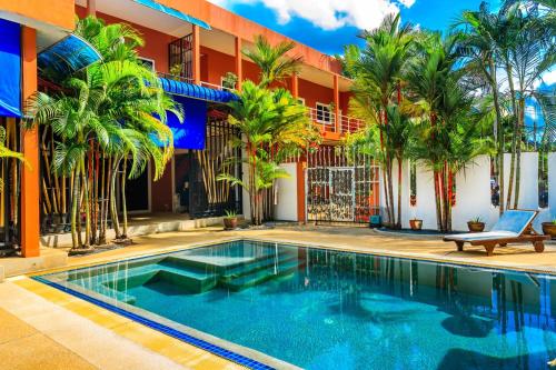 a swimming pool in front of a building with palm trees at Jungceylon Villa - quiet location, pool, maid in Patong Beach