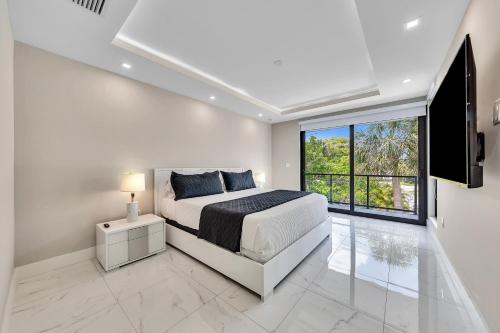 a white bedroom with a bed and a large window at VillaPlaya brand new home, modern style resort! in Fort Lauderdale