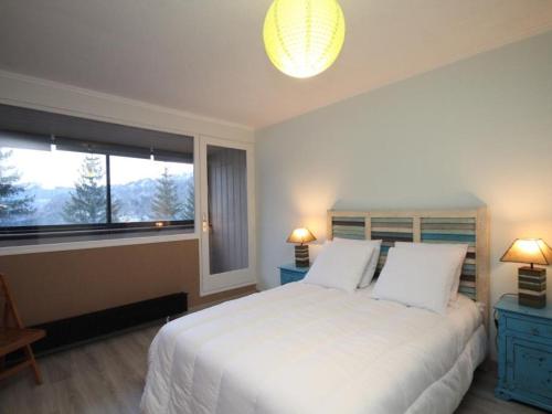 ein Schlafzimmer mit einem großen weißen Bett und einem Fenster in der Unterkunft Appartement T4 dernier étage au centre avec wifi et parking - FR-1-608-9 in Le Mont-Dore