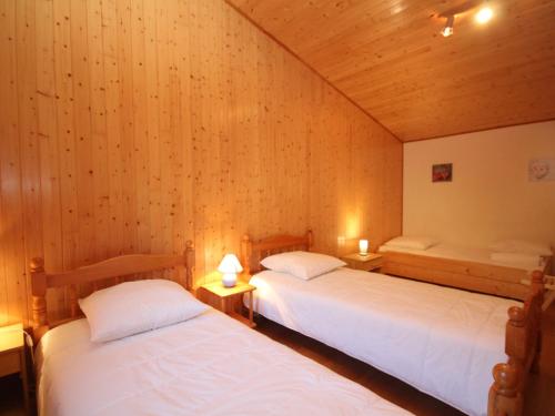 deux lits dans une chambre aux murs en bois dans l'établissement Mont-Dore : Duplex 4P avec Balcon, Garage et Wi-Fi - FR-1-608-3, à Le Mont-Dore