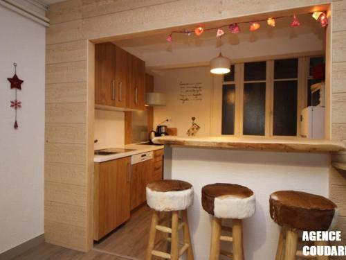 - une cuisine avec des placards en bois et des tabourets dans la chambre dans l'établissement Hyper Centre Mont-Dore: Duplex T3 avec WiFi, 8 Pers - FR-1-608-1, à Le Mont-Dore