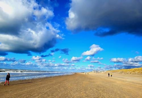 una playa con gente caminando por la arena en zilvermeeuw, en Bergen aan Zee