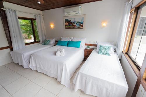 two beds in a room with white walls and windows at Pousada Maria Maria Búzios in Búzios