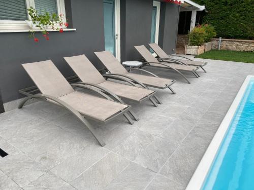 a row of chaise lounge chairs next to a swimming pool at LHV Garda Lake - Private POOL and SPA in Bardolino