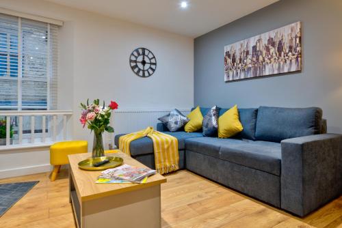 a living room with a blue couch and a table at 2-Bed Apartment in Stamford Town Centre-Parking & Wi-Fi in Stamford