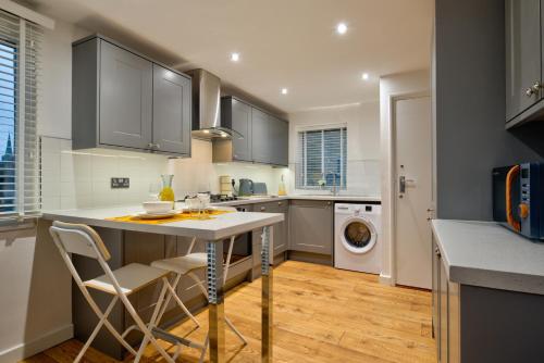 a kitchen with gray cabinets and a table and chairs at 2-Bed Apartment in Stamford Town Centre-Parking & Wi-Fi in Stamford