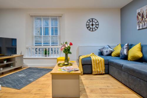 a living room with a blue couch and yellow pillows at 2-Bed Apartment in Stamford Town Centre-Parking & Wi-Fi in Stamford