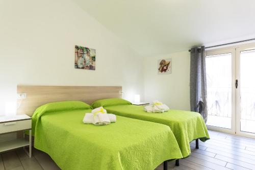 una camera con due letti verdi con asciugamani di Residence Rossomelograno ad Agropoli