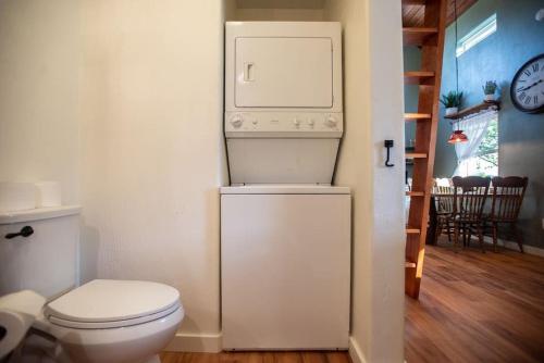 a bathroom with a toilet and a washer and dryer at Cowbell Cabin 15min to Downtown Waco in Waco