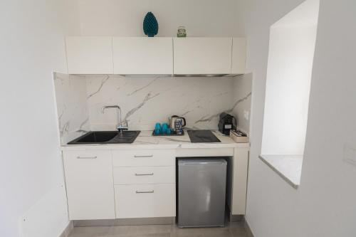 a white kitchen with a sink and a dishwasher at Panorama Alfeo in Siracusa