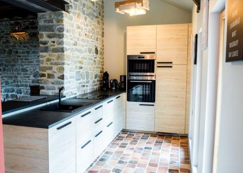 - une cuisine avec des placards blancs et un mur en pierre dans l'établissement Le Fournil du Bertry, à La Bouexière