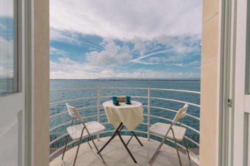 a table and chairs on a balcony with a view of the ocean at Panorama Alfeo in Siracusa