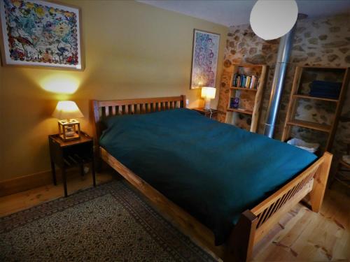 a bedroom with a large wooden bed with a blue bedspread at Chez-Judith in Boussenac