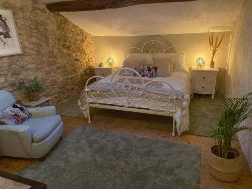 a bedroom with a white bed and a stone wall at Figtrees in Margueron
