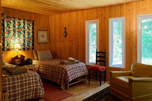 a bedroom with two beds and a chair and windows at Black River Cottage in Milford