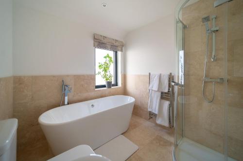 un bagno bianco con vasca e doccia di Seymour Heights a Woolacombe
