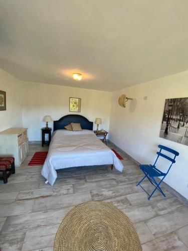sypialnia z dużym łóżkiem i niebieskim krzesłem w obiekcie Los Mirlos w mieście La Cumbre