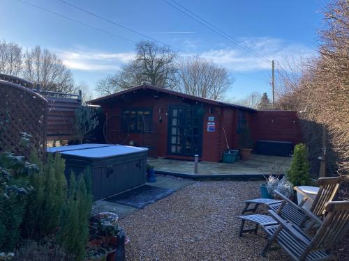 una pequeña casa roja con un patio con 2 sillas en Easthorpe Retreat, en Colchester