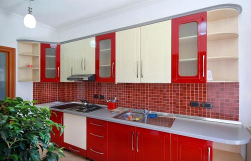 una cocina con armarios rojos y blancos y fregadero en My Home Guest House, en Durrës
