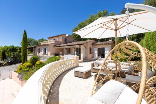 une terrasse avec une balançoire et un parasol dans l'établissement Villa La Bonne Etoile The Perfect Family Oasis, à Les Adrets-de-l'Estérel