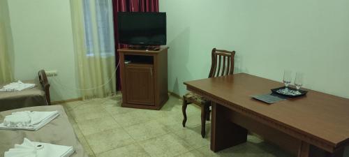 SWEET HOME HOTEL Meghri في Meghri: غرفة بطاولة خشبية وتلفزيون