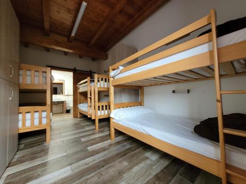 1 dormitorio con 3 literas y suelo de madera en La Cala Hostel en Loredo
