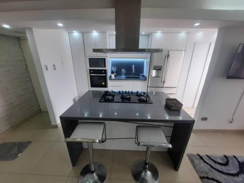 uma cozinha com um fogão e um balcão com dois bancos em Apartamento ubicado en Bellas Artes em Caracas