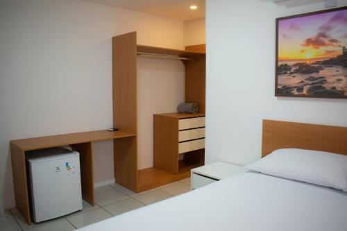 a small bedroom with a bed and a desk at POUSADA PEDRA DE JACÓ in Lauro de Freitas