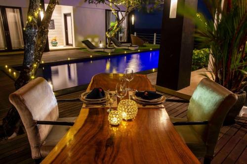 a wooden table with two chairs and a pool at Nusa Dua Ocean View 4 Bedroom Bibi Bali in Nusa Dua