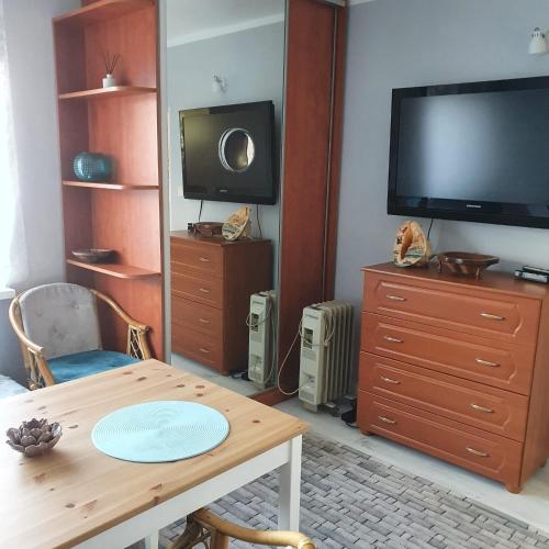 a living room with a table and a flat screen tv at Sztormowa 13 in Chałupy
