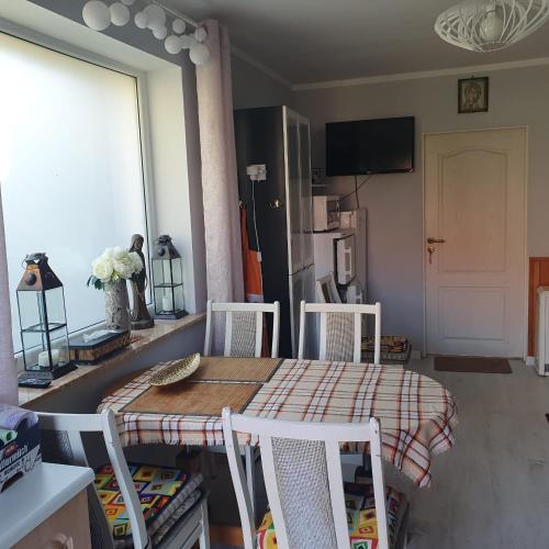 a dining room with a table and chairs and a kitchen at Sztormowa 13 in Chałupy
