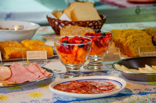 a table topped with bowls of food and bread at Pousada Rancho Das Framboesas in Visconde De Maua