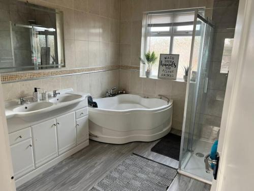 a bathroom with a tub and two sinks and a shower at The BIG one! Large Holiday Home Blackpool. 3 floors of luxury. in Blackpool