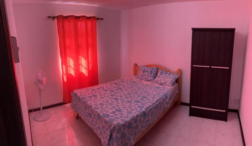 a bedroom with a bed and a red curtain at 3 mins - 15 mins to the beach in Trou aux Biches