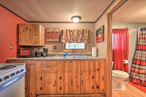 a kitchen with wooden cabinets and a sink and a toilet at Matt Dillon Cabin about 1 Mile to Raystown Lake! in Huntingdon