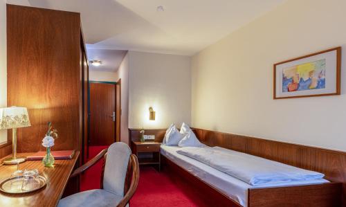 a bedroom with a bed and a desk and a chair at Hotel Katharinenhof STANDARD in Dornbirn
