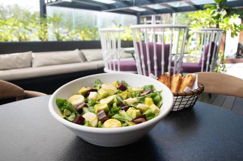 a bowl of salad on a table with a basket of bread at The Xperience by g in Mazatlán