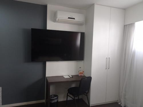 um quarto com uma secretária e uma televisão na parede em Apartamento San Diego Pampulha Propriedade Particular em Belo Horizonte