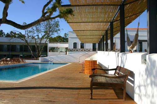 a wooden deck with a bench next to a swimming pool at Alentejo Star Hotel - Sao Domingos - Mertola - Duna Parque Resorts & Hotels in Mina de São Domingos