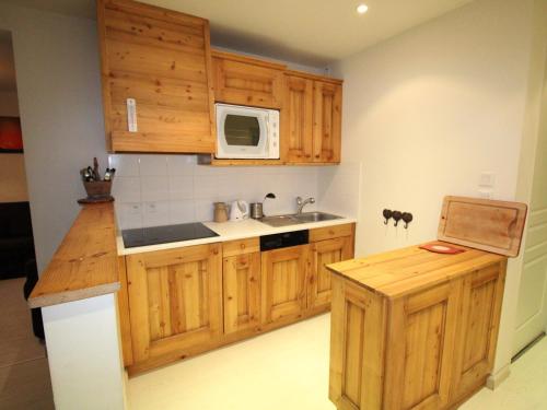 La cuisine est équipée de placards en bois, d'un évier et d'un four micro-ondes. dans l'établissement Bel Appartement à Avoriaz - Village Hauts Forts, 6 Pers, 66m² avec Terrasse, 3 Chambres - FR-1-633-8, à Avoriaz