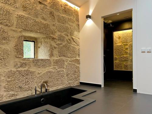a bathroom with a black sink and a stone wall at Quinta da Porta - Solar de Vale de Prazeres in Vale de Prazeres
