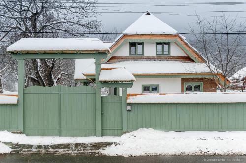 a green fence in front of a house with snow at Dimineți în Cerdac in Piatra Neamţ