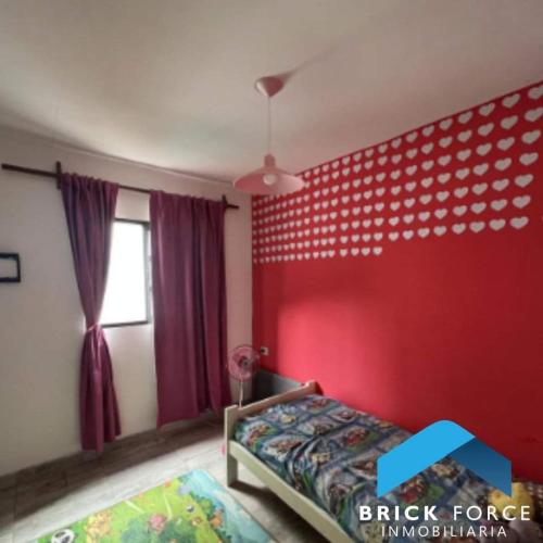 1 dormitorio con pared roja, cama y ventana en Hermoso Dúplex 2 Dormitorios en San Miguel de Tucumán