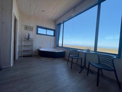een kamer met een bad, 2 stoelen en een tafel bij Cabaña para 2 con jacuzzi campo mar in Matanzas
