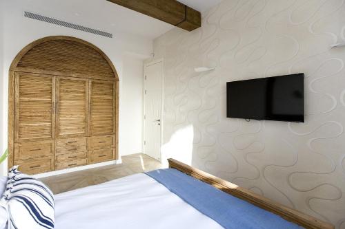 a bedroom with a bed and a flat screen tv at Molcho Neve Tzedek in Tel Aviv