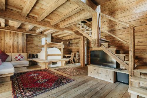 Cabaña de madera con sala de estar con techo de madera y TV. en Luxury Cortina, en Cortina dʼAmpezzo