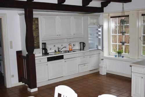 uma cozinha com armários brancos, um lavatório e uma janela em Ferienwohnungen Manfred Peters Baven em Hermannsburg