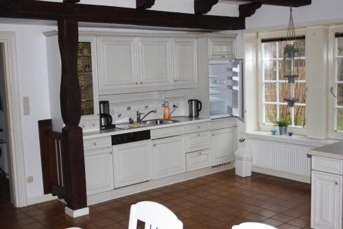 a kitchen with white cabinets and a sink and a window at Ferienwohnungen Manfred Peters Baven in Hermannsburg