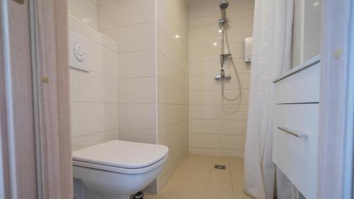 La salle de bains blanche est pourvue d'une douche et de toilettes. dans l'établissement Sunny Aisa Apartment, à Pärnu