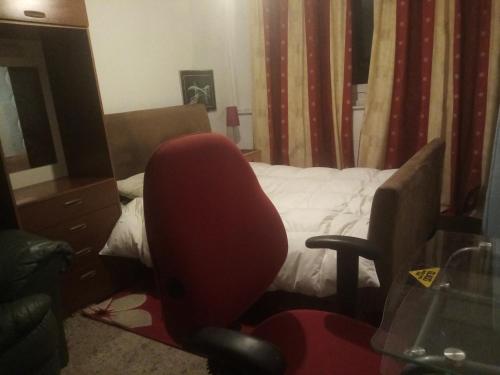 een kamer met een rode bureaustoel voor een bed bij Flat 30 brookeshouse in Walsall